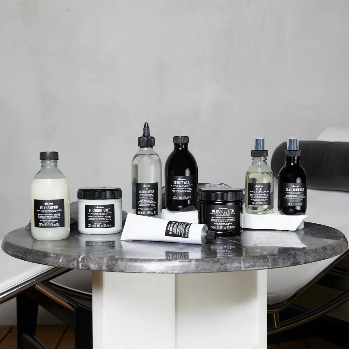 Collection of Davines OI products on a marble table with a neutral background